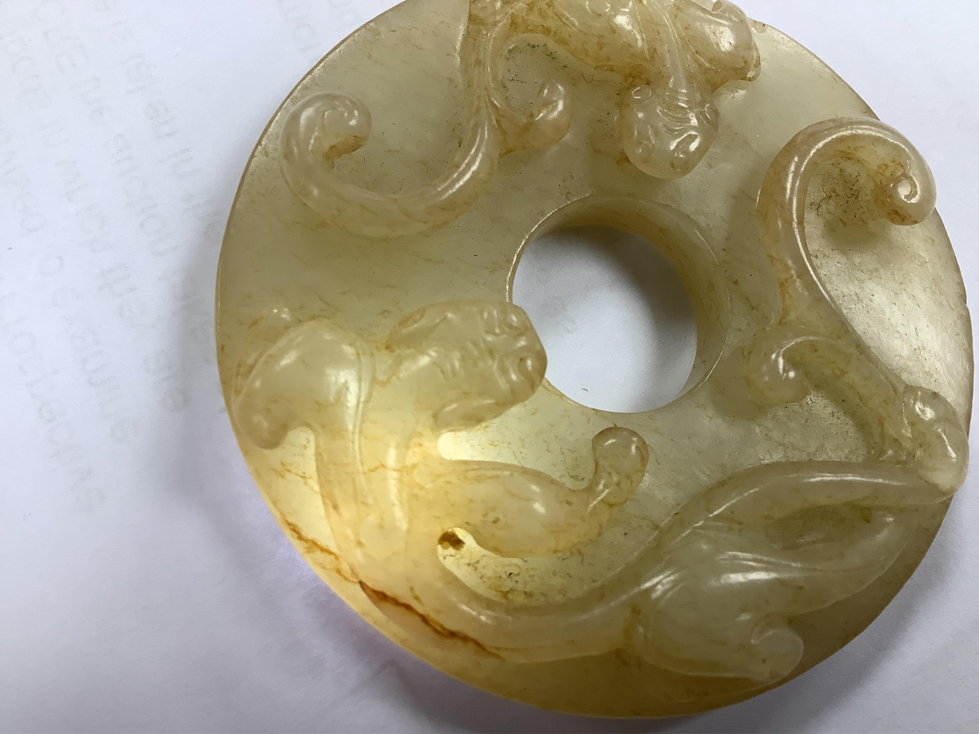 An 18th century Chinese mottled jade bi disc, decorated with two carved chilong, 5.8cm diameter